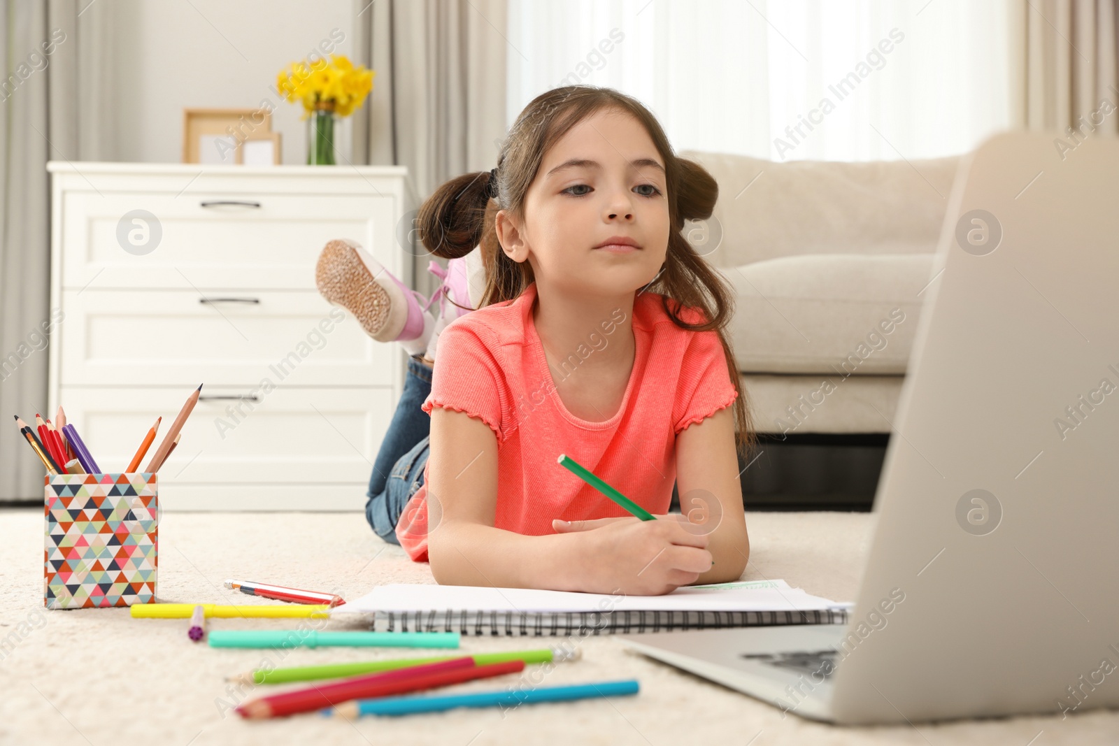 Little girl drawing on paper with pencil at online lesson indoors. Distance learning Photo of Little girl drawing on paper with pencil at online lesson indoors. Distance learning