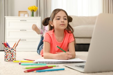 Little girl drawing on paper with pencil at online lesson indoors. Distance learning Photo of Little girl drawing on paper with pencil at online lesson indoors. Distance learning