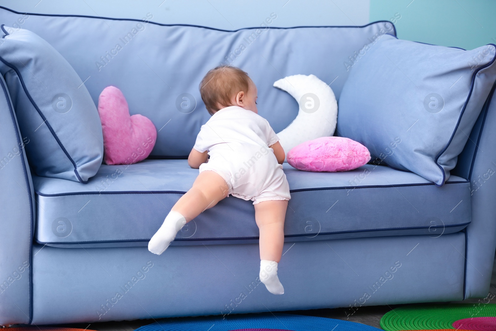 Cute baby climbing on couch in living room Photo of Cute baby climbing on couch in living room
