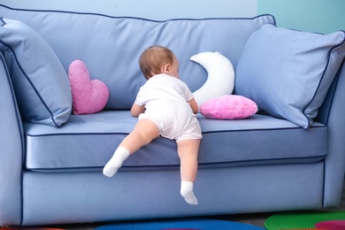 Cute baby climbing on couch in living room Photo of Cute baby climbing on couch in living room
