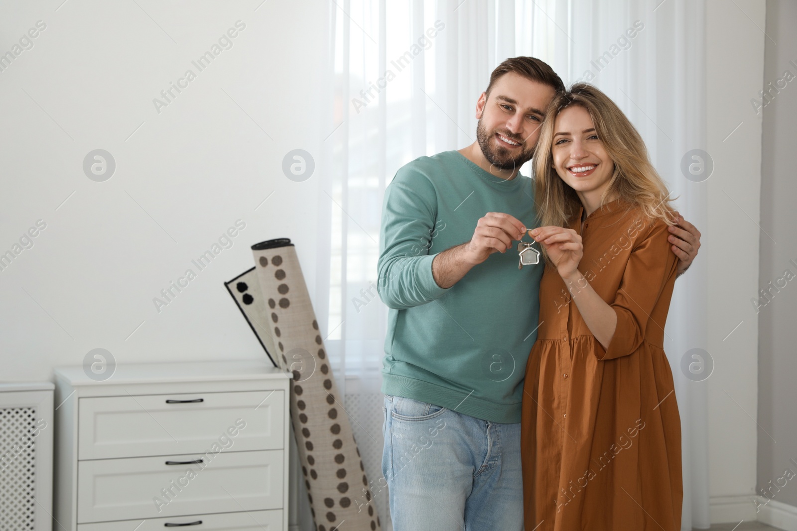 Happy young couple with key in new house. Space for text Photo of Happy young couple with key in new house. Space for text
