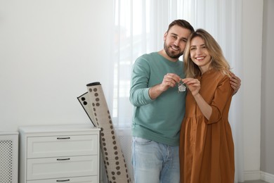 Happy young couple with key in new house. Space for text Photo of Happy young couple with key in new house. Space for text
