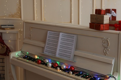White piano with festive decor and note sheets indoors. Christmas music Photo of White piano with festive decor and note sheets indoors. Christmas music