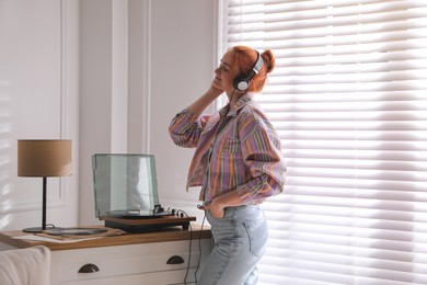 Young woman listening to music with turntable at home Photo of Young woman listening to music with turntable at home