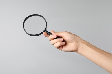 Woman holding magnifying glass on grey background, closeup. Find keywords concept Photo of Woman holding magnifying glass on grey background, closeup. Find keywords concept