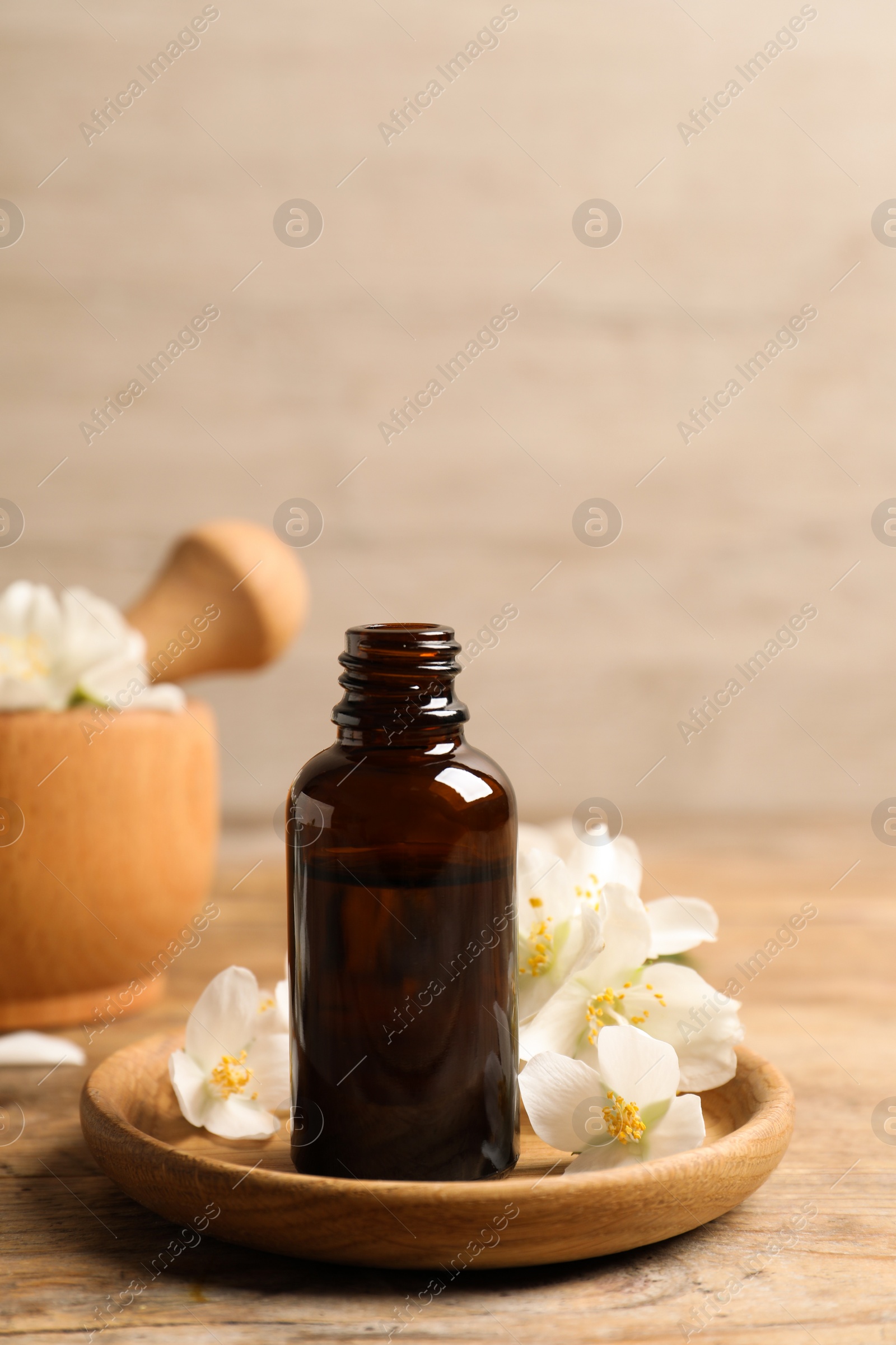 Jasmine essential oil and fresh flowers on wooden table Photo of Jasmine essential oil and fresh flowers on wooden table