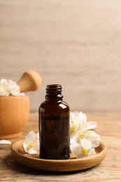 Jasmine essential oil and fresh flowers on wooden table Photo of Jasmine essential oil and fresh flowers on wooden table