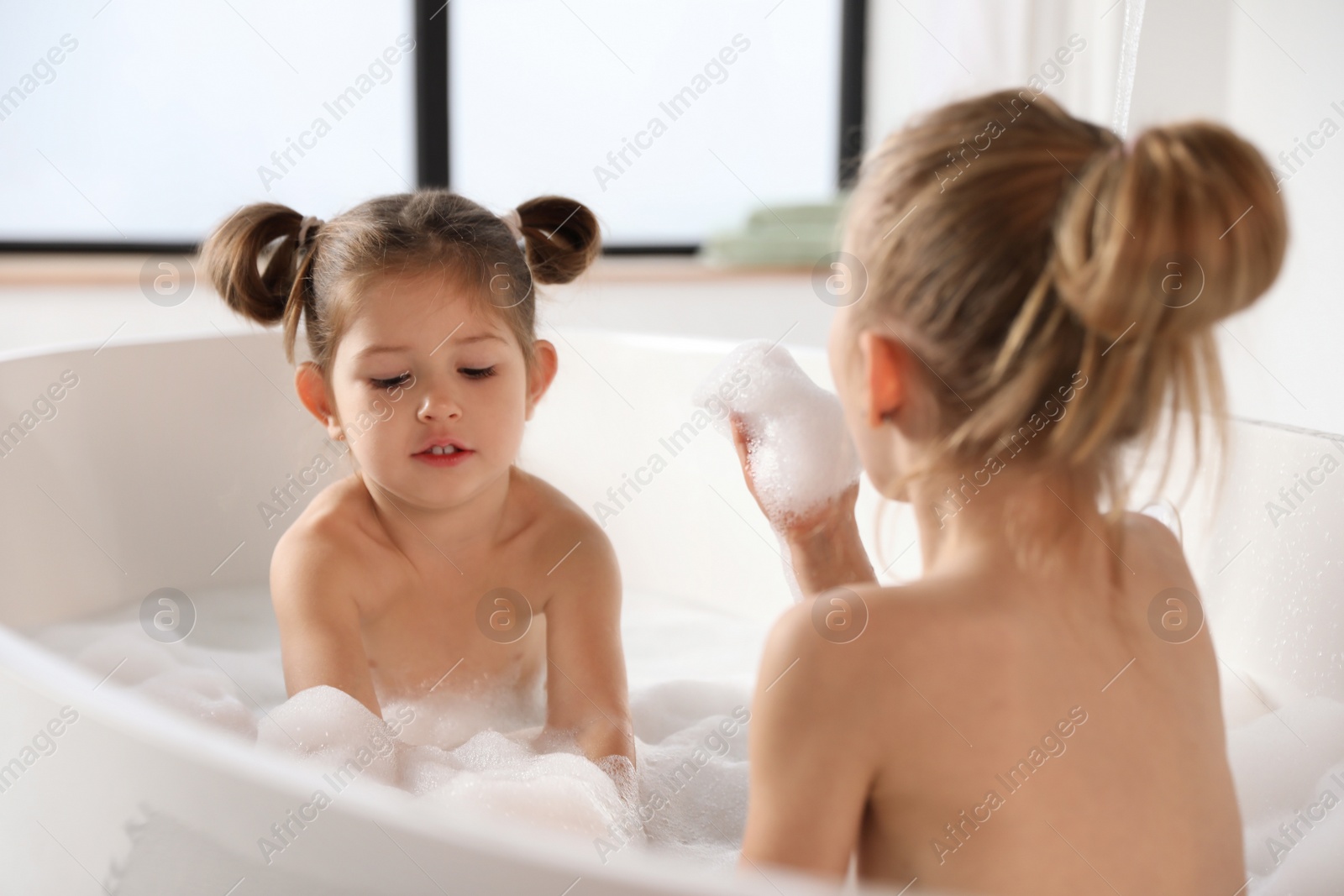 Cute little sisters taking bubble bath together Photo of Cute little sisters taking bubble bath together