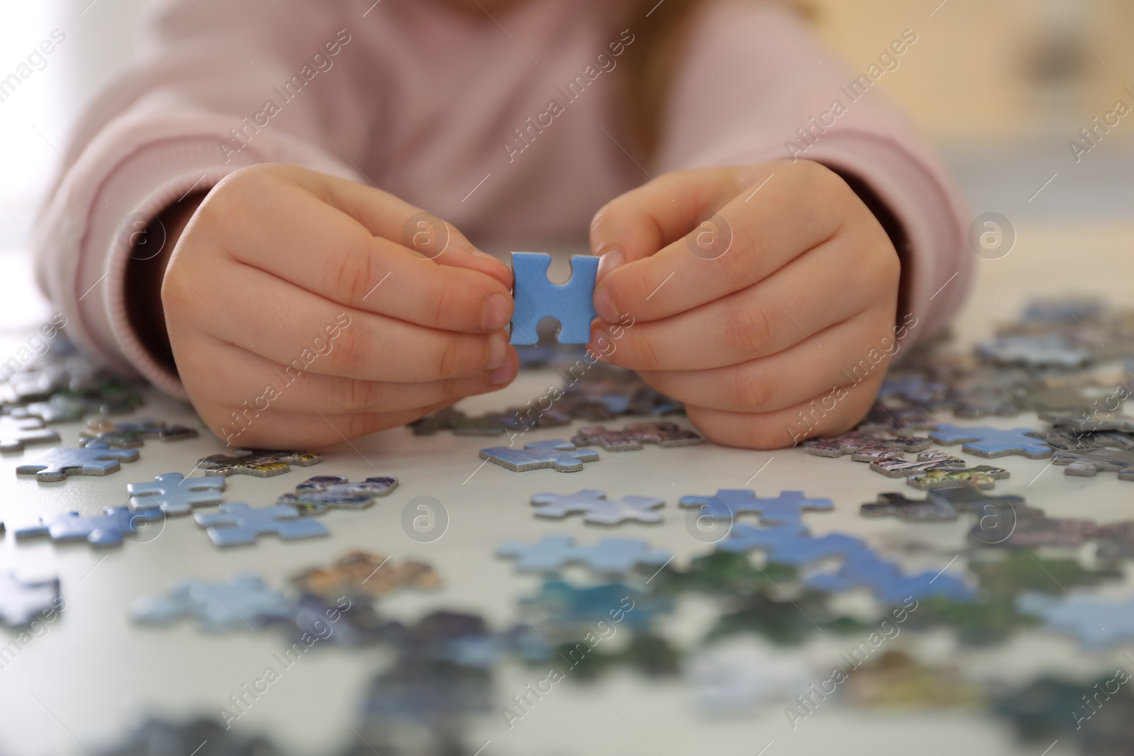 Little child playing with puzzles at table, closeup Photo of Little child playing with puzzles at table, closeup