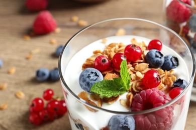 Tasty dessert with yogurt, berries and granola on wooden table, closeup Image of Tasty dessert with yogurt, berries and granola on wooden table, closeup