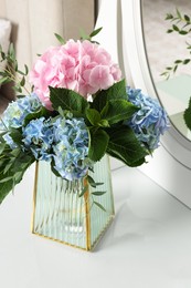 Beautiful hortensia flowers in vase on dressing table indoors Photo of Beautiful hortensia flowers in vase on dressing table indoors
