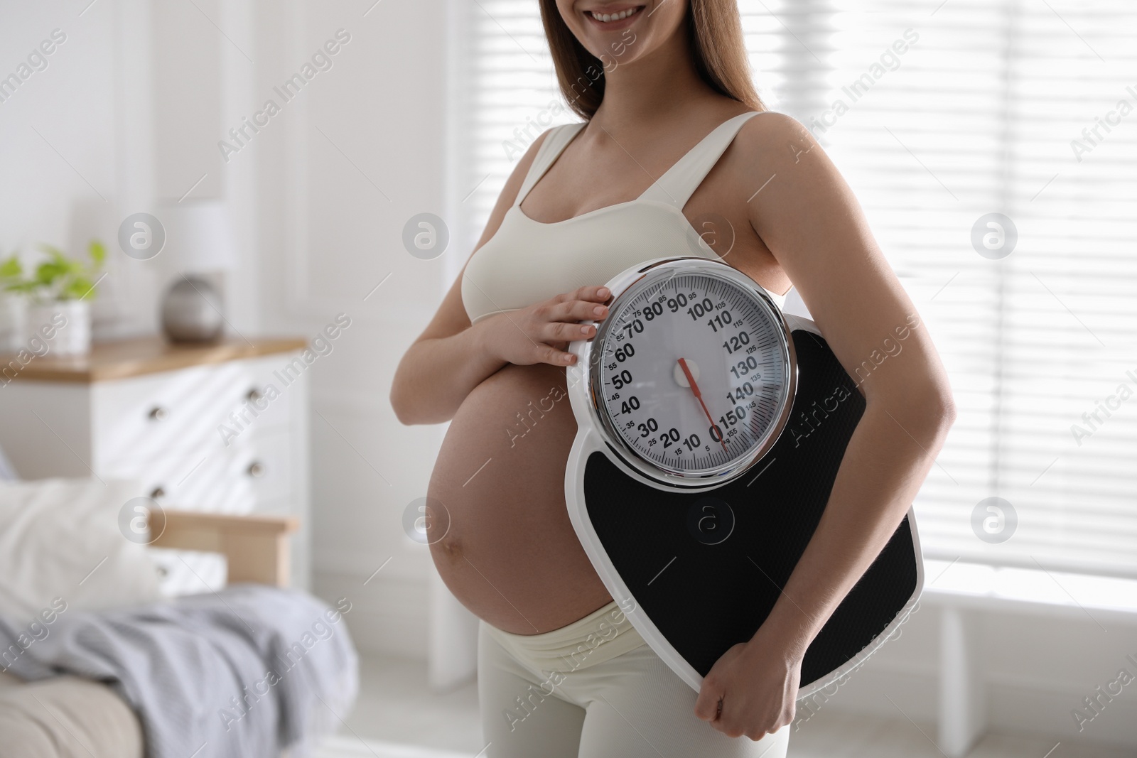 Young pregnant woman with scales at home, closeup Photo of Young pregnant woman with scales at home, closeup