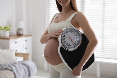 Young pregnant woman with scales at home, closeup Photo of Young pregnant woman with scales at home, closeup