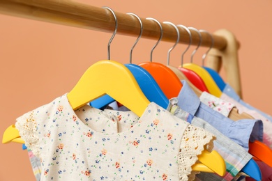 Rack with stylish children clothes on beige background, closeup Photo of Rack with stylish children clothes on beige background, closeup
