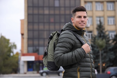 Photo of Male tourist with travel backpack on city street. Urban trip