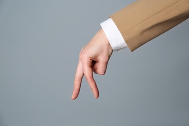 Businesswoman imitating walk with hand on grey background, closeup. Finger gesture Photo of Businesswoman imitating walk with hand on grey background, closeup. Finger gesture