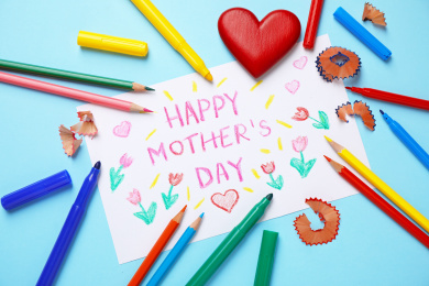 Photo of Flat lay composition with drawing for Mother's day on light blue background