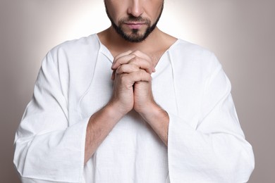 Religious man with clasped hands praying against grey background, closeup Photo of Religious man with clasped hands praying against grey background, closeup