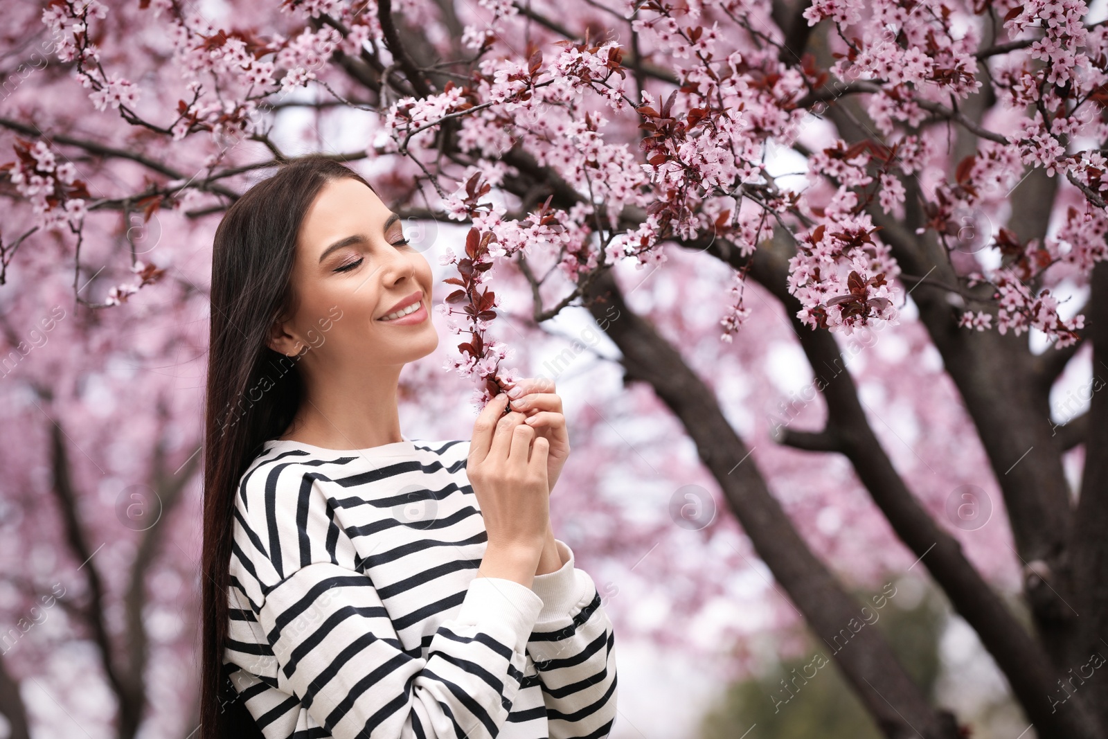 Pretty young woman near blooming tree in park. Spring look Photo of Pretty young woman near blooming tree in park. Spring look