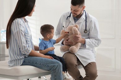 Photo of Mother and son visiting pediatrician in hospital. Doctor playing with little boy