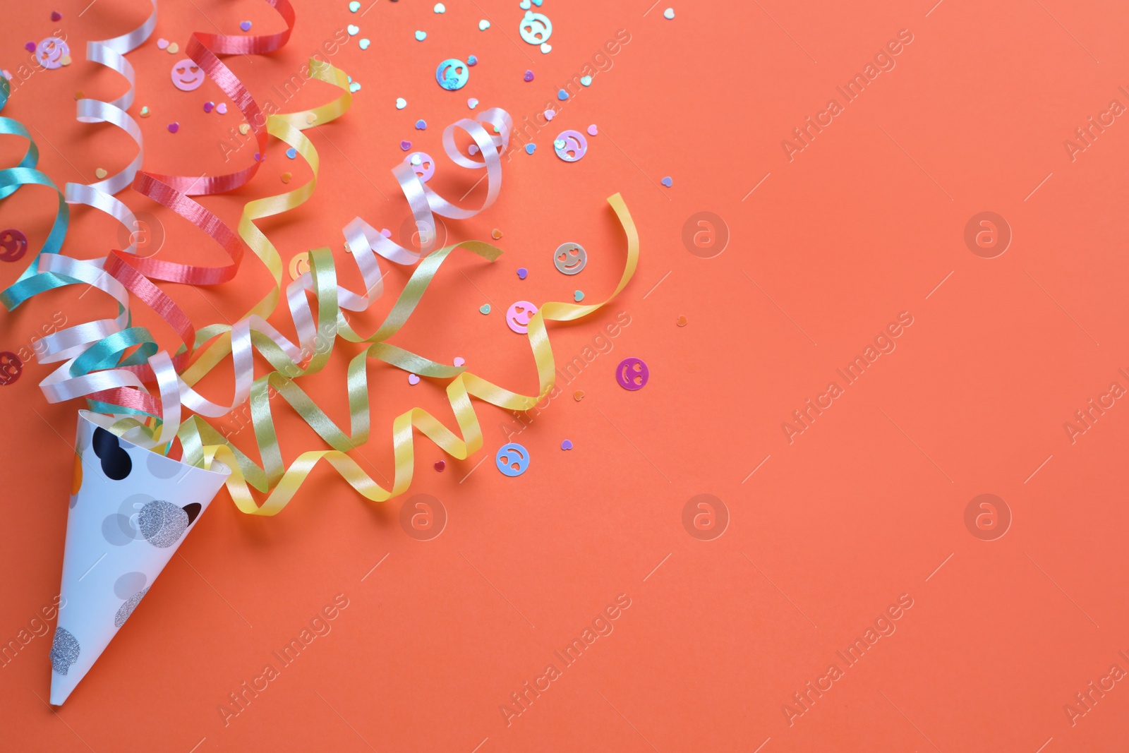 Colorful confetti and streamers with party cracker on orange background, top view. Space for text Photo of Colorful confetti and streamers with party cracker on orange background, top view. Space for text