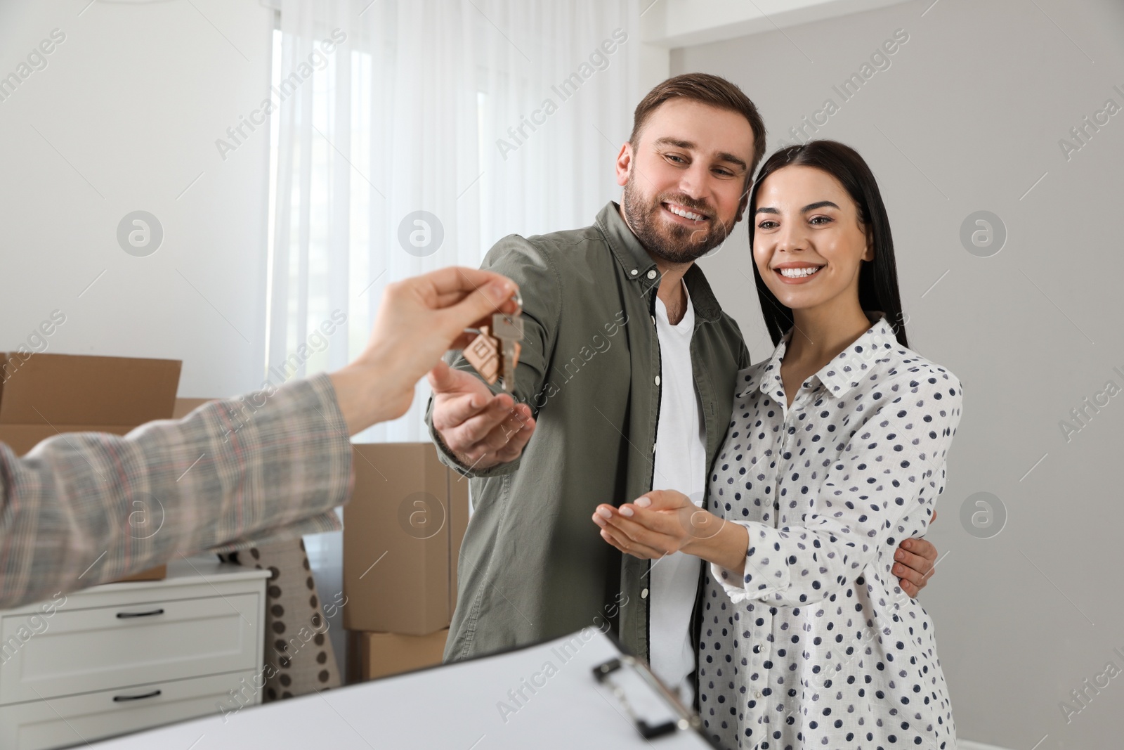 Real estate agent giving key to happy young couple in new house Photo of Real estate agent giving key to happy young couple in new house
