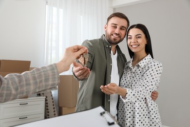 Real estate agent giving key to happy young couple in new house Photo of Real estate agent giving key to happy young couple in new house