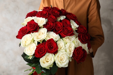 Woman holding luxury bouquet of fresh roses on beige background, closeup Photo of Woman holding luxury bouquet of fresh roses on beige background, closeup