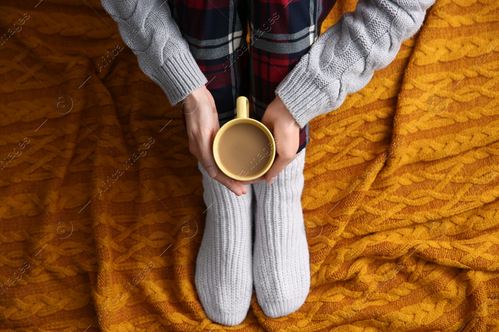 Woman relaxing with cup of hot winter drink on knitted plaid, top view. Cozy season Photo of Woman relaxing with cup of hot winter drink on knitted plaid, top view. Cozy season