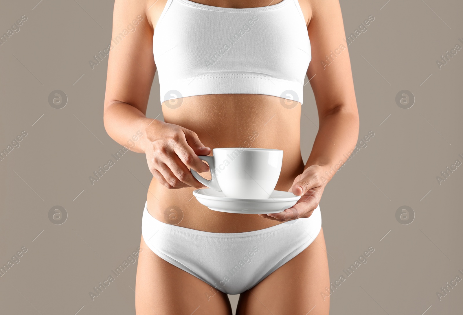 Young woman holding cup of diet tea on beige background, closeup Photo of Young woman holding cup of diet tea on beige background, closeup
