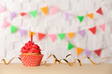 Birthday cupcake with candle against blurred background Photo of Birthday cupcake with candle against blurred background