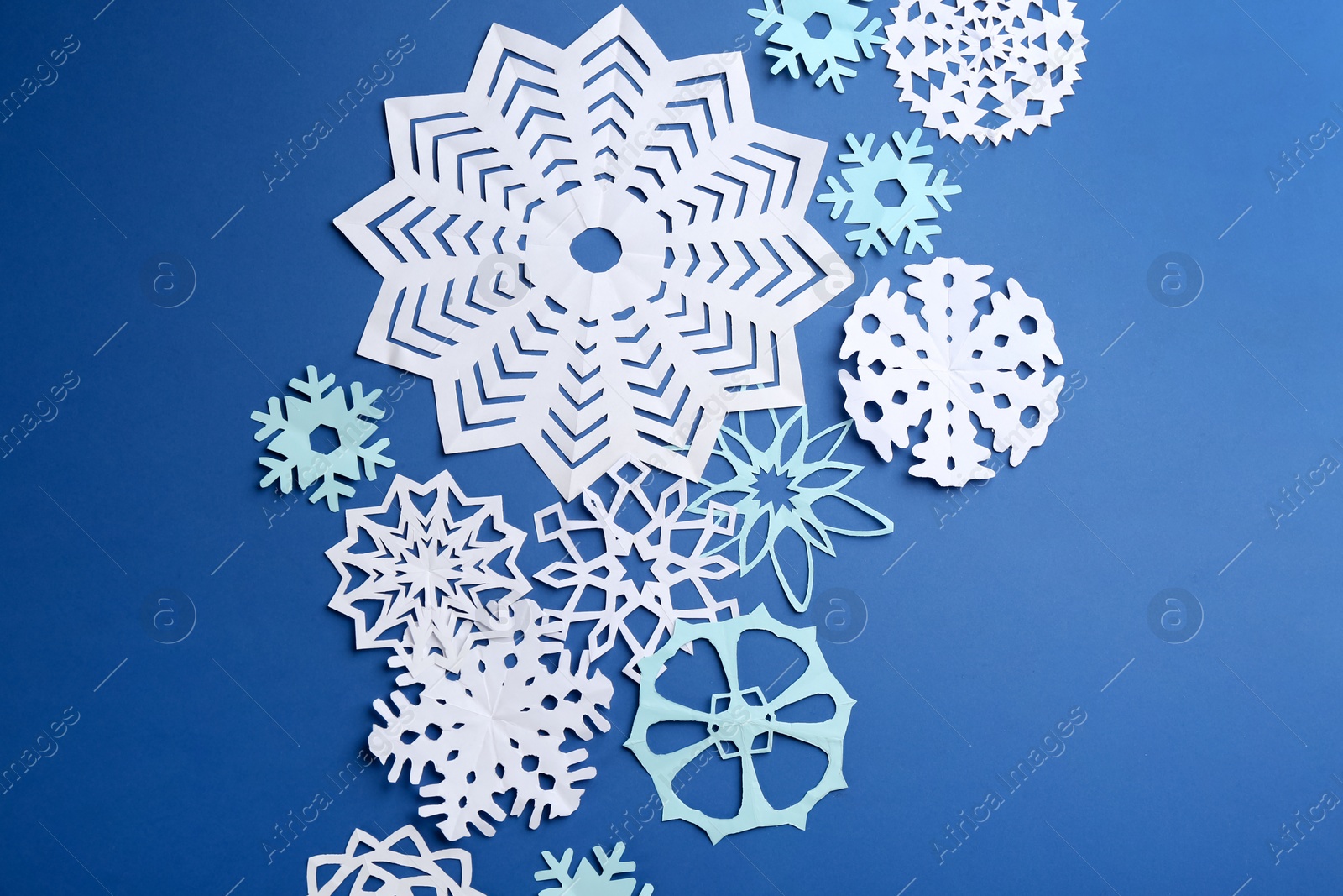 Many paper snowflakes on blue background, flat lay Photo of Many paper snowflakes on blue background, flat lay