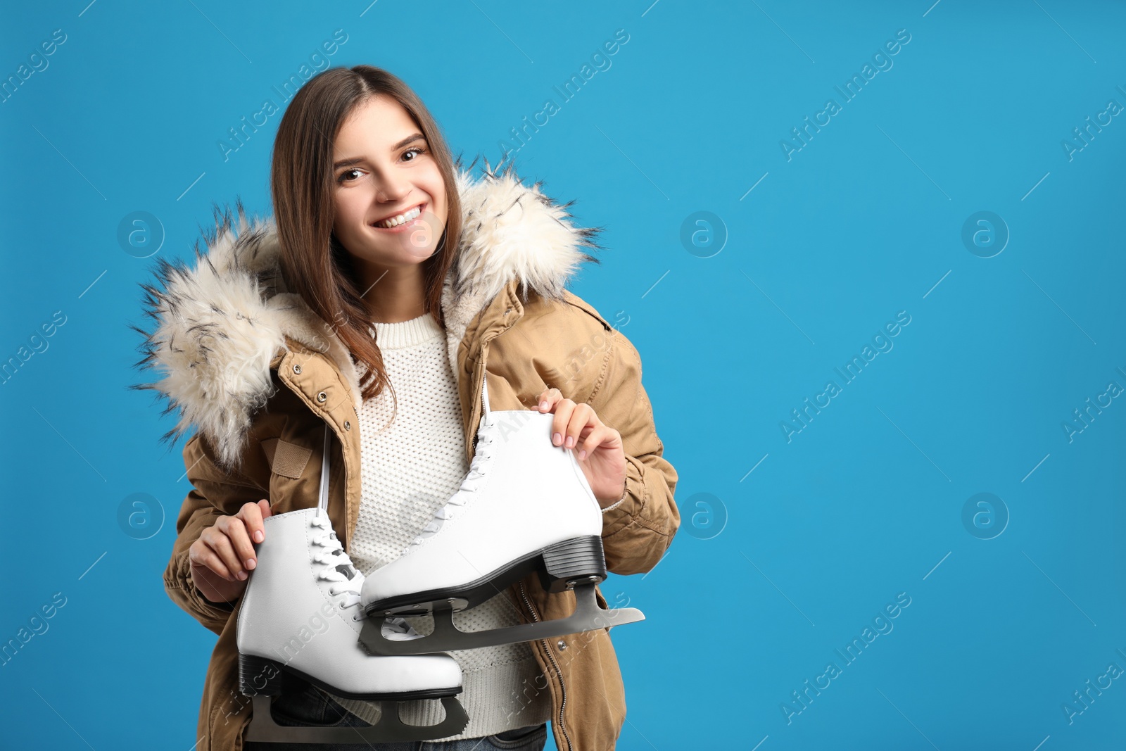 Happy woman with ice skates on light blue background. Space for text Photo of Happy woman with ice skates on light blue background. Space for text