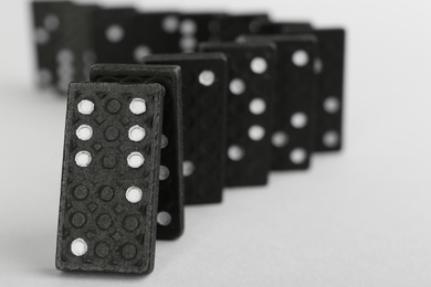 Black domino tiles falling on white background. Space for text Photo of Black domino tiles falling on white background. Space for text