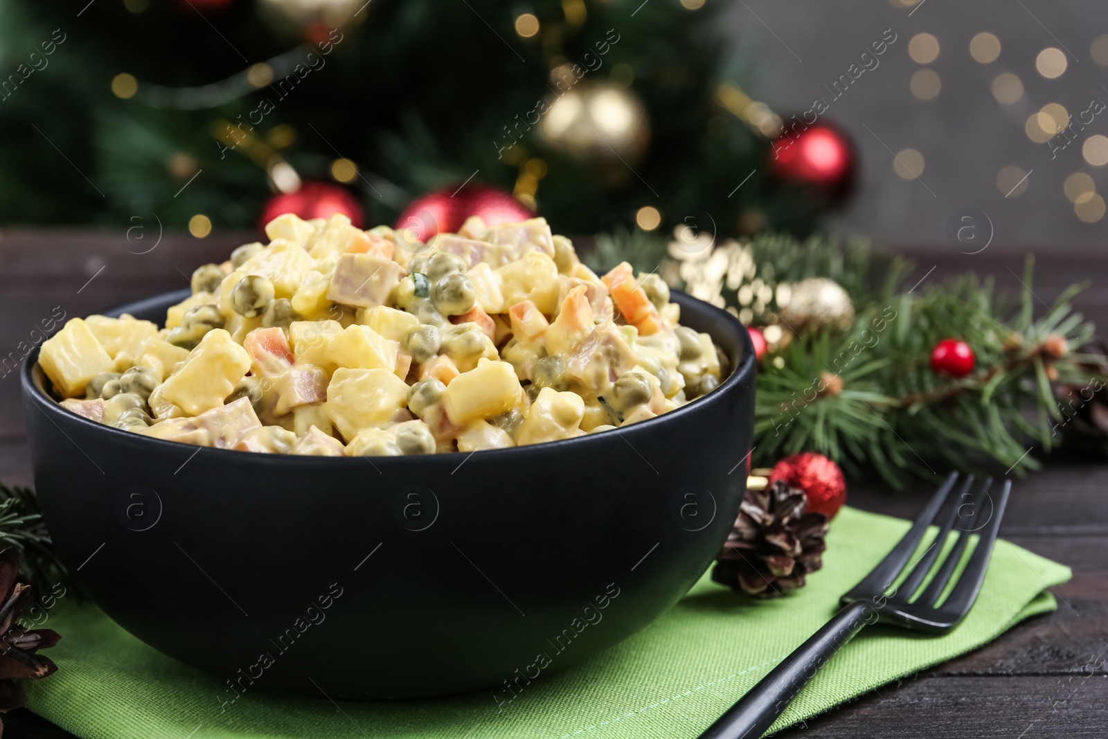 Photo of Fresh Russian salad Olivier in black bowl on table, closeup