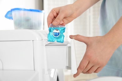Woman putting laundry detergent capsule into washing machine, closeup Photo of Woman putting laundry detergent capsule into washing machine, closeup