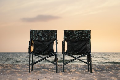 Camping chairs on sandy beach near sea Photo of Camping chairs on sandy beach near sea