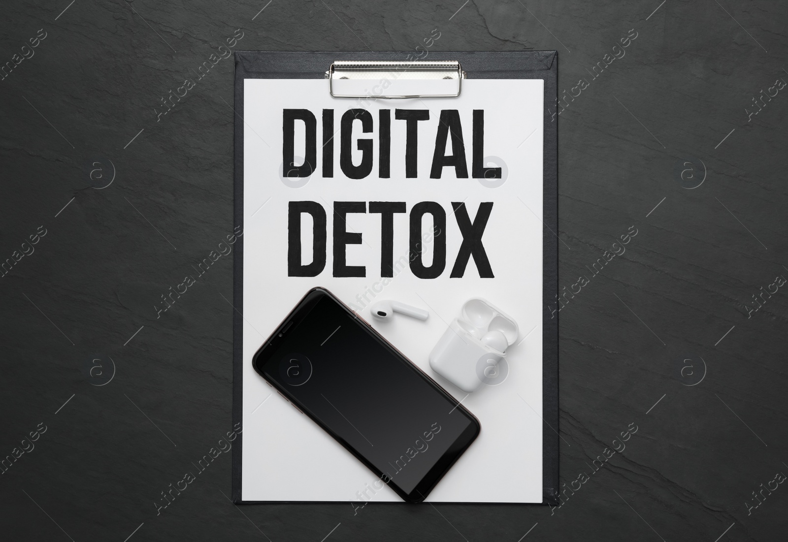 Clipboard with phrase DIGITAL DETOX, smartphone and earphones on black stone table, flat lay Photo of Clipboard with phrase DIGITAL DETOX, smartphone and earphones on black stone table, flat lay