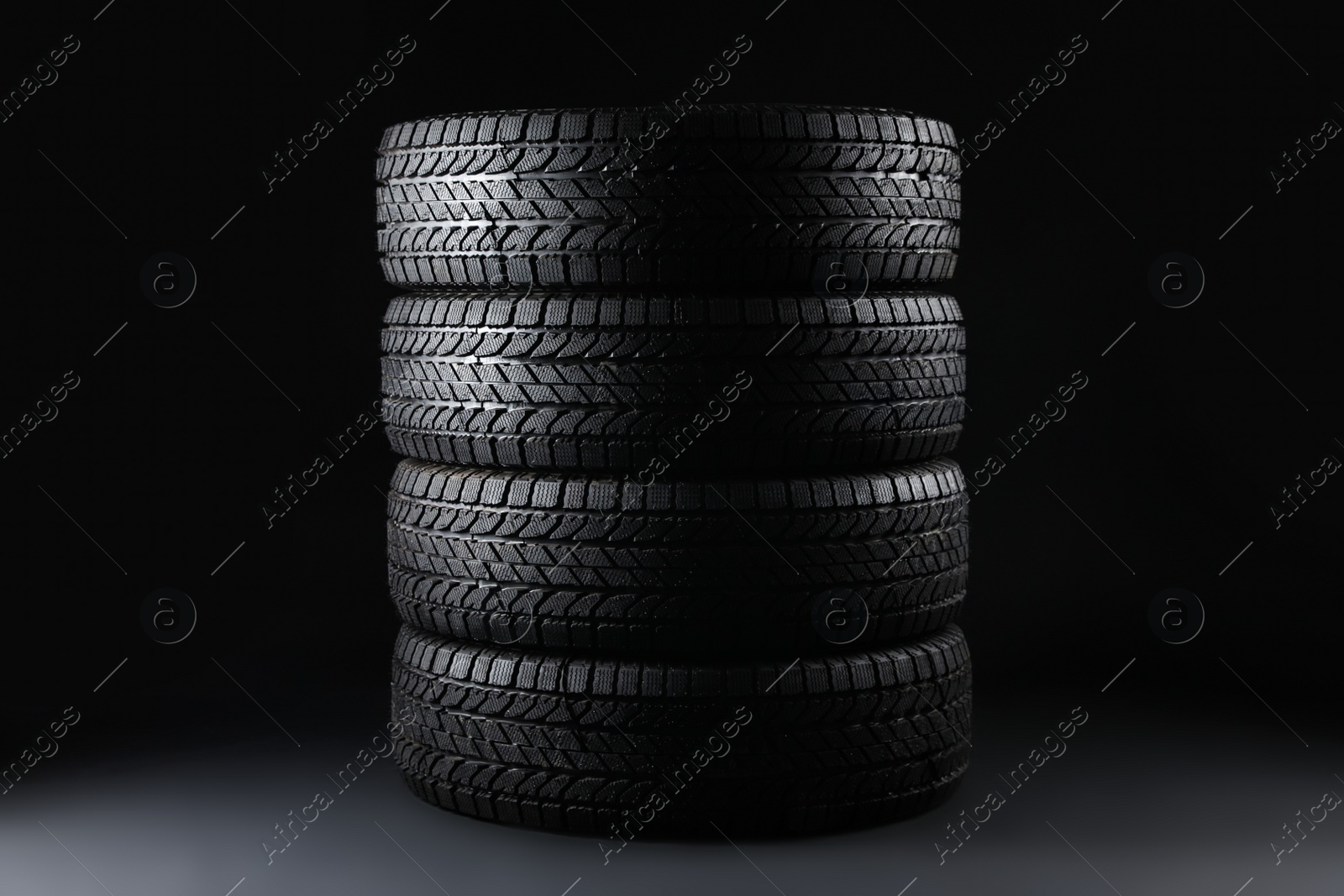 Stacked winter tires on black background. Car maintenance Photo of Stacked winter tires on black background. Car maintenance
