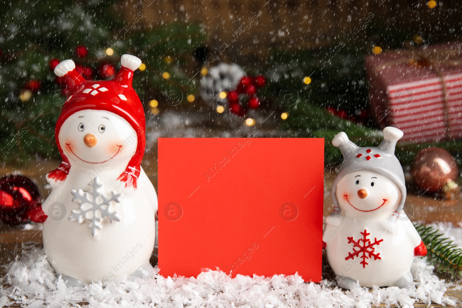 Funny decorative snowmen and blank red card on table Photo of Funny decorative snowmen and blank red card on table