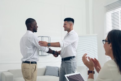 Boss shaking hand with new employee and coworkers applauding in office Photo of Boss shaking hand with new employee and coworkers applauding in office