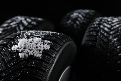 Photo of Snowy set of wheels with winter tires on black background, closeup. Space for text