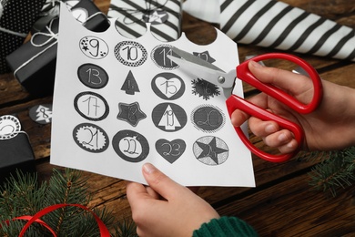 Woman making advent calendar at wooden table, closeup Photo of Woman making advent calendar at wooden table, closeup