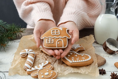 Woman holding delicious homemade Christmas cookie at wooden table, closeup Photo of Woman holding delicious homemade Christmas cookie at wooden table, closeup