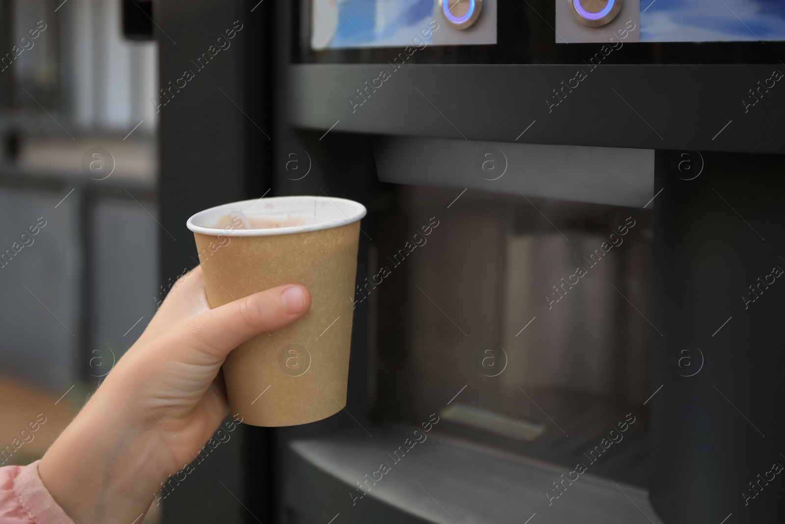 Girl holding paper cup with drink near coffee and hot beverage vending machine, closeup. Space for text Photo of Girl holding paper cup with drink near coffee and hot beverage vending machine, closeup. Space for text