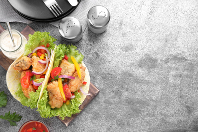 Photo of Delicious fish tacos served on grey table flat lay with space for text. Traditional Mexican dish