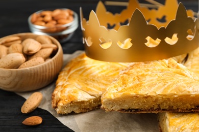 Traditional galette des Rois with paper crown on black wooden table, closeup Photo of Traditional galette des Rois with paper crown on black wooden table, closeup