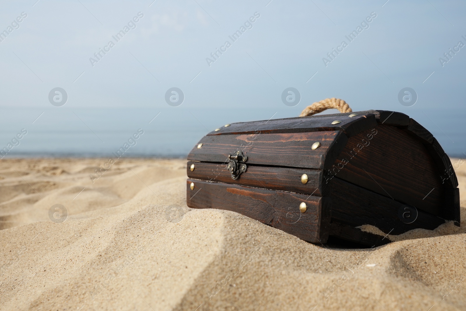 Closed wooden treasure chest on sandy beach, space for text Photo of Closed wooden treasure chest on sandy beach, space for text