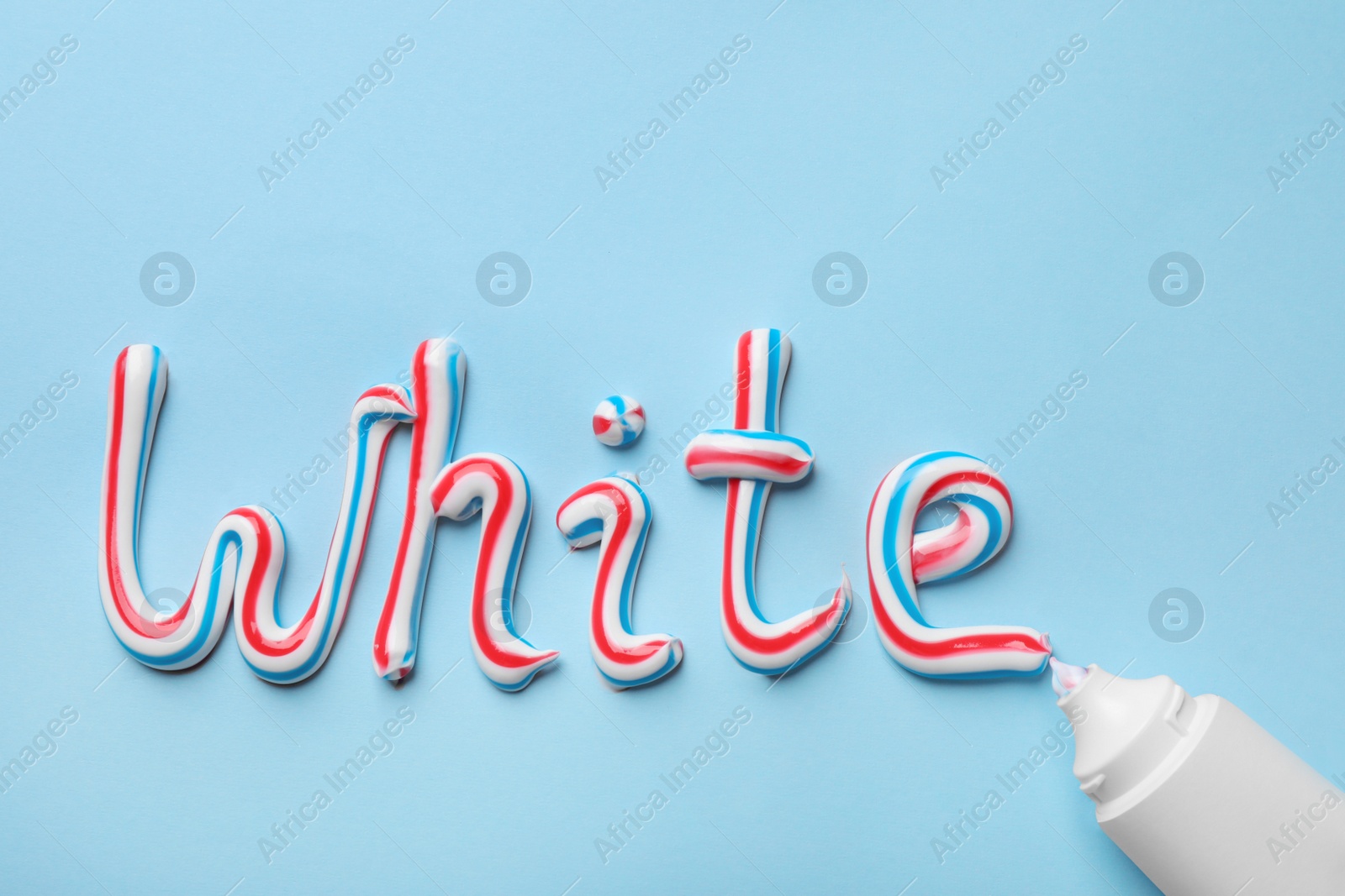 Tube and word White made of toothpaste on light blue background, flat lay Photo of Tube and word White made of toothpaste on light blue background, flat lay