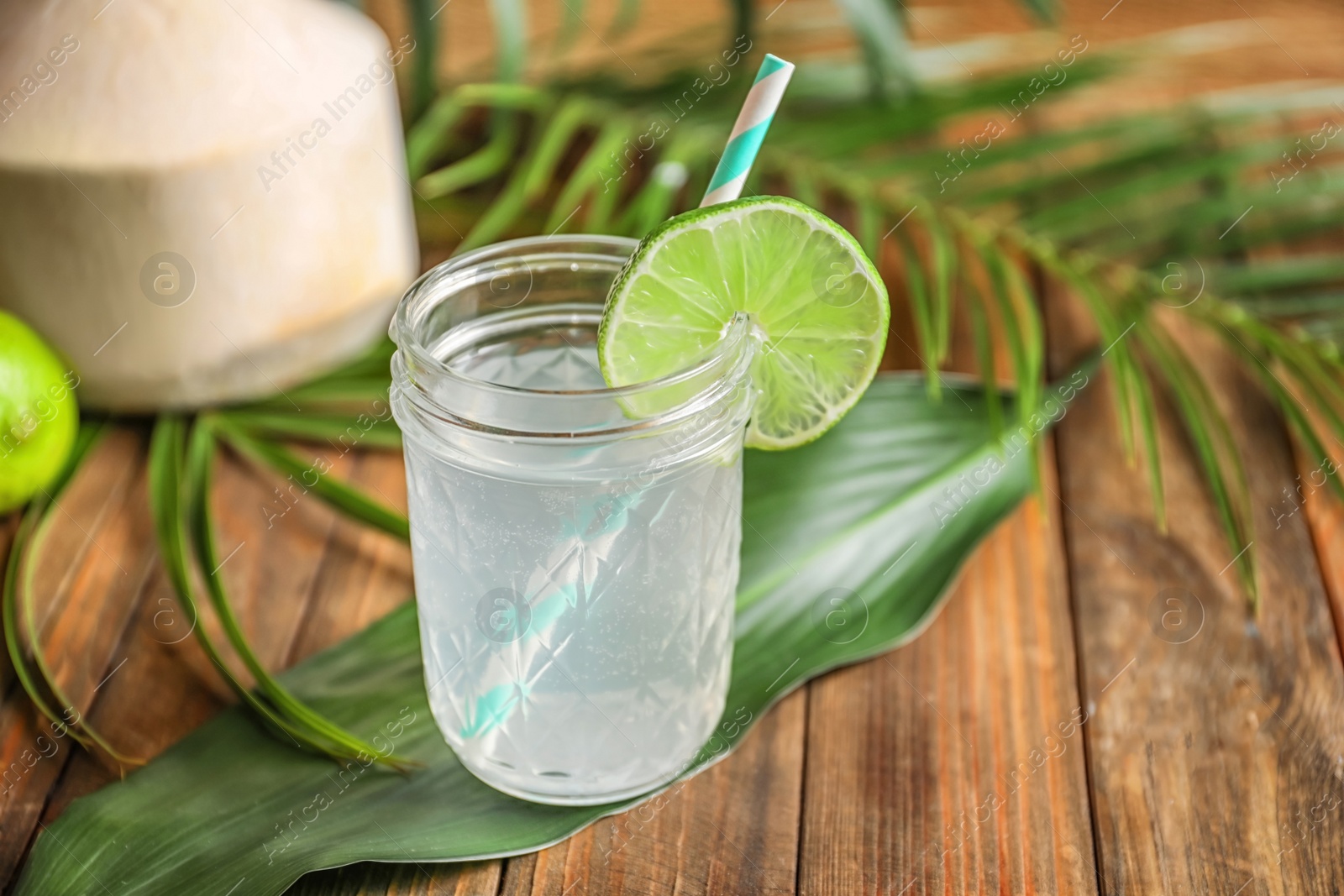Jar with fresh coconut water and lime on wooden table Photo of Jar with fresh coconut water and lime on wooden table